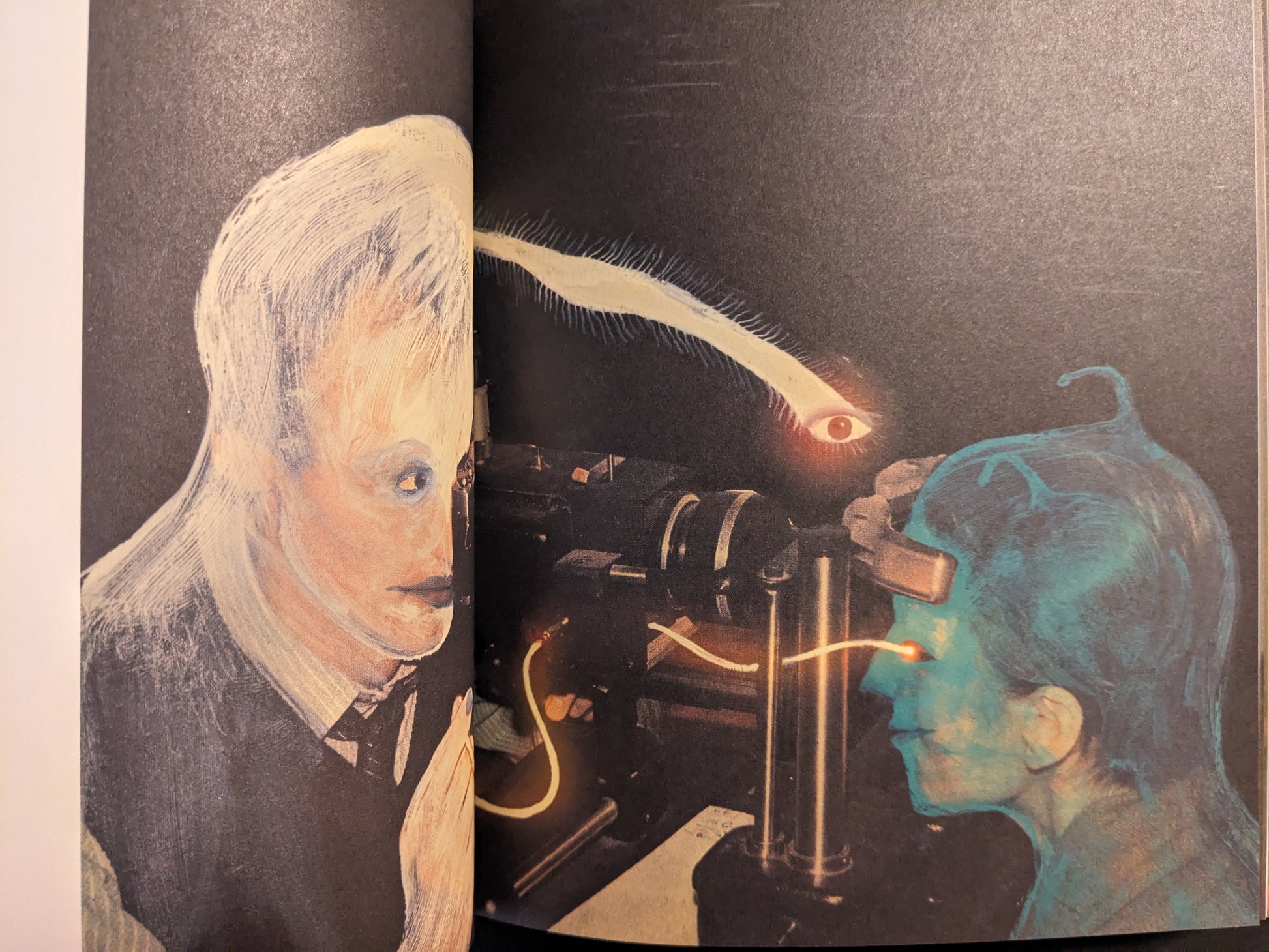 Interior double-page spread from In a Dark Time, the Eye Begins to See by Julia Soboleva, with two portraits facing a machine and a floating eye above.