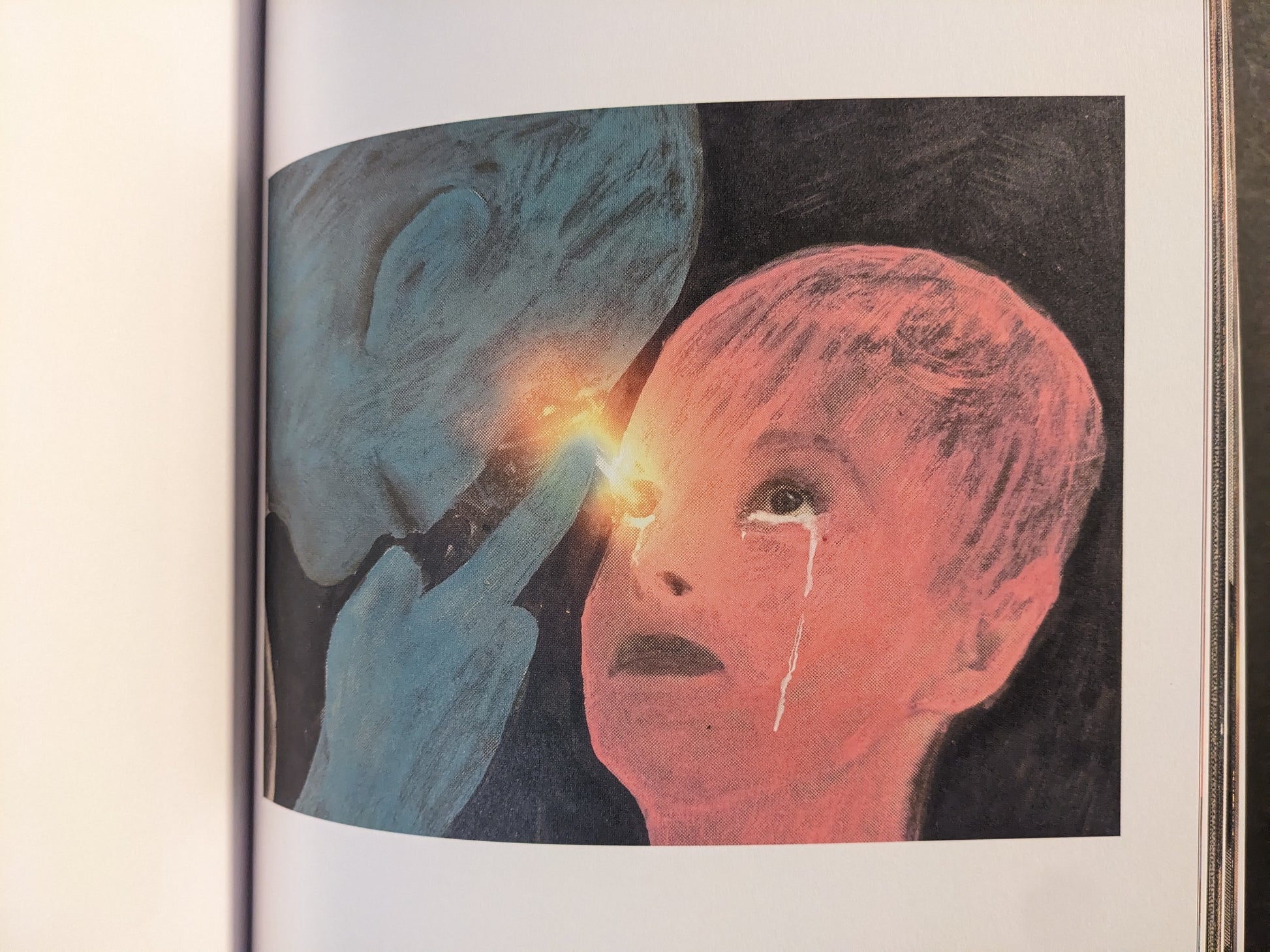 Interior artwork showing a blue hand holding a bright light near a red face with tear streaks.