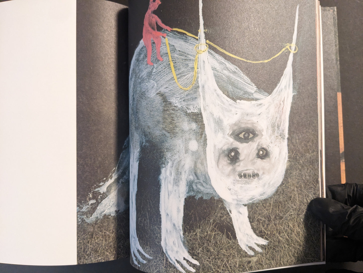 Interior artwork showing a pale multi-eyed creature hanging from ropes, with a small red figure above.