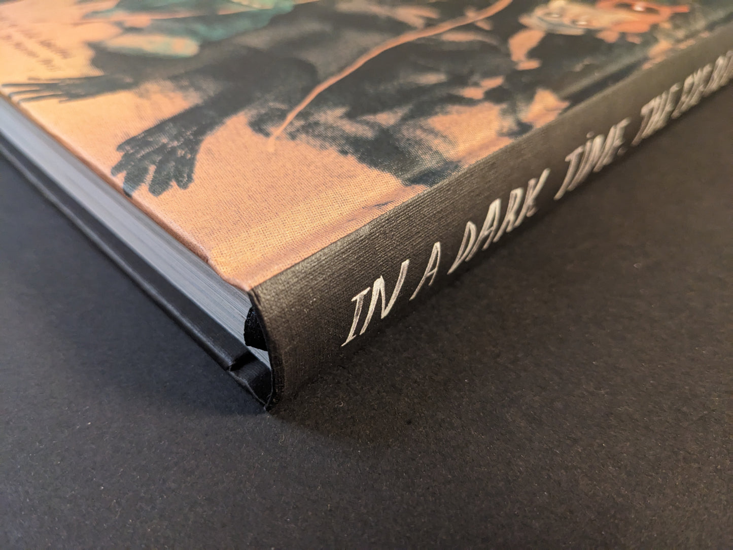 Spine detail of “In a Dark Time, the Eye Begins to See: The Art of Julia Soboleva” with white title lettering on black cloth.