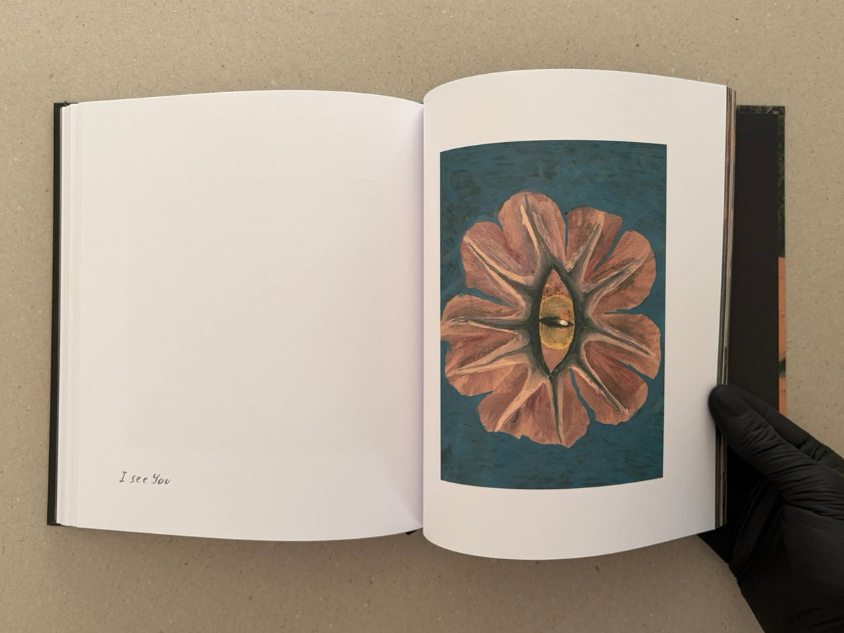 Open artbook spread from In a Dark Time, the Eye Begins to See – The Art of Julia Soboleva, showing a blank left page with the text 'I see You' and a right page with a framed painting of a flower-like form around a central eye.