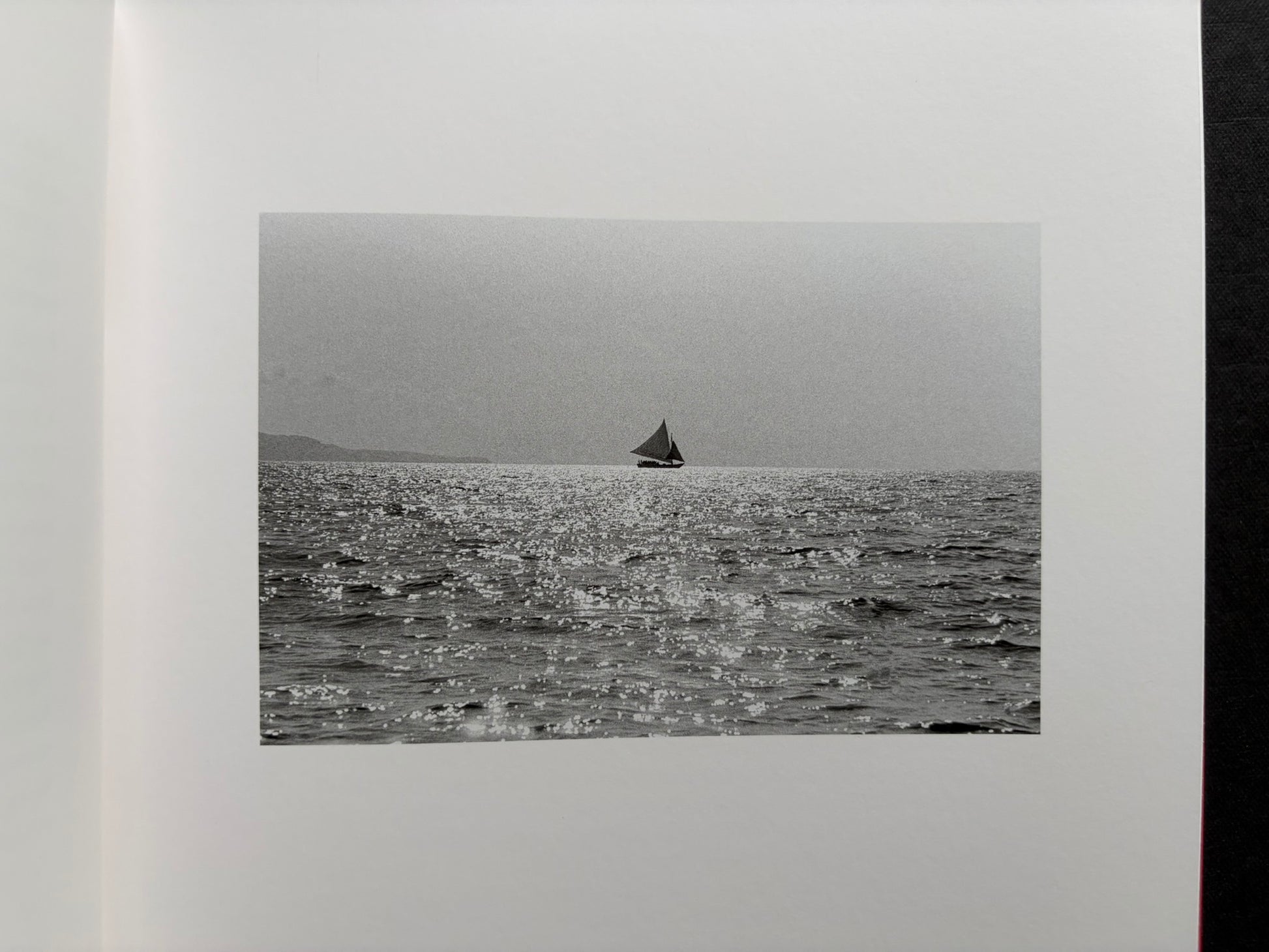 Index by Christopher Anderson, black-and-white seascape with a small sailboat near the horizon.