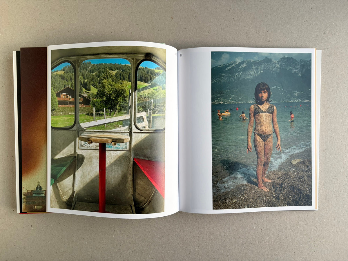 Open Index — Christopher Anderson booklet with a window view and a child standing in shallow water by a mountain lake.