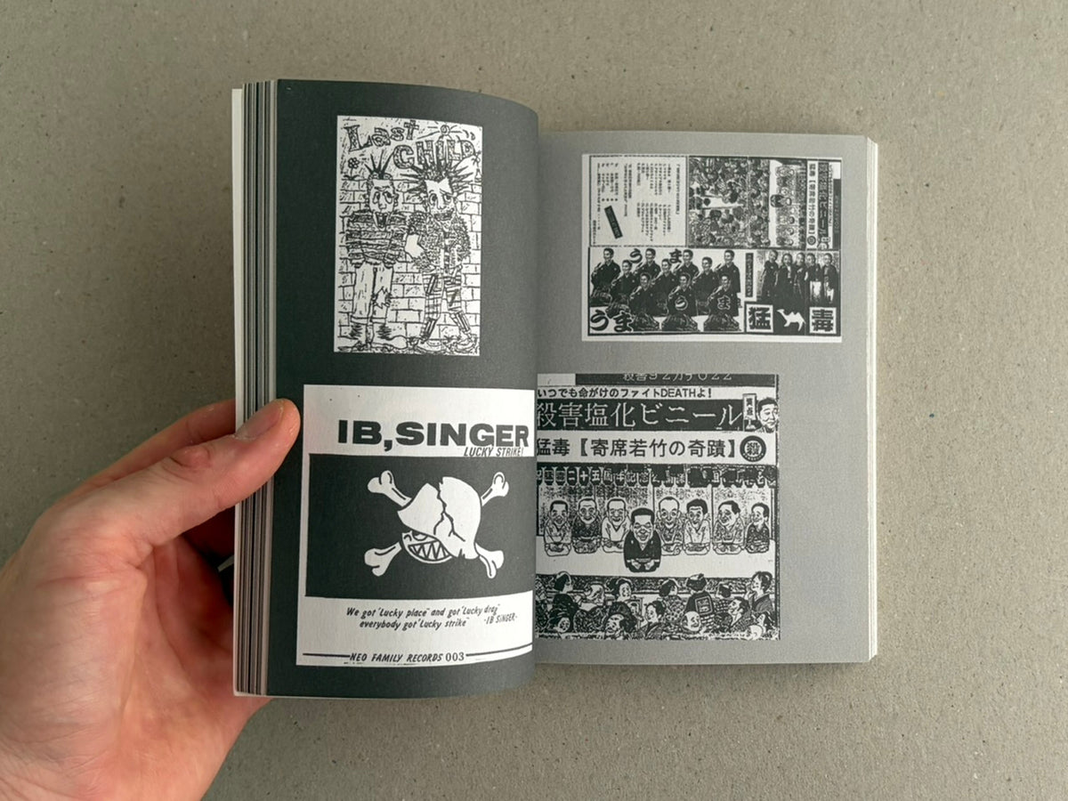 Open book spread from Japanese Punk Graphics (1980-2010) showing black-and-white punk graphics and Japanese text, held open by a hand.