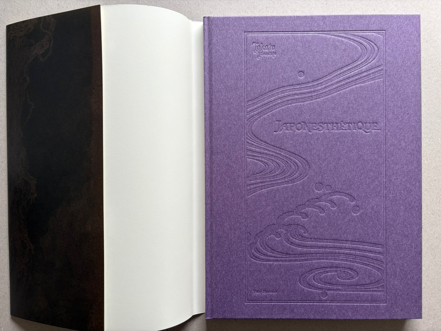 Japonesthétique by Takato Yamamoto opened to the purple embossed cover and front endpaper.