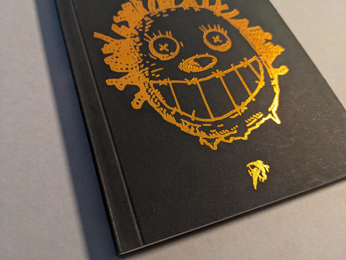 Close-up of the embossed gold foil cover illustration on black.