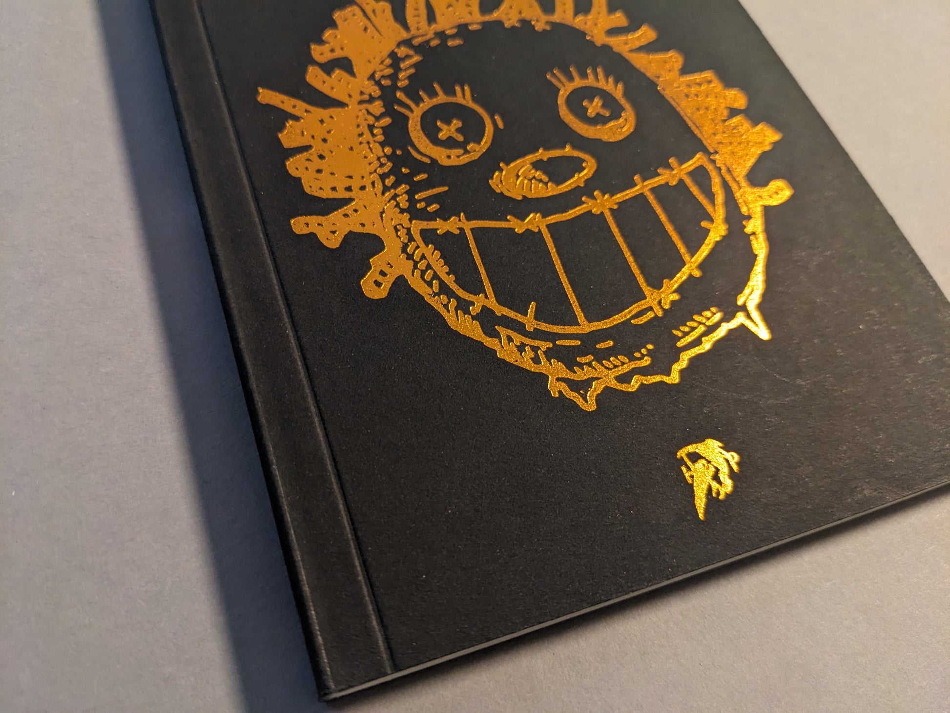 Close-up of the embossed gold foil cover illustration on black.
