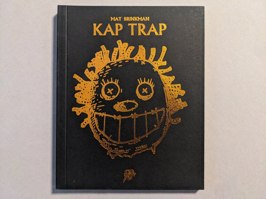 Front cover of KAP TRAP by Mat Brinkman, featuring a gold foil illustration on black hardcover.