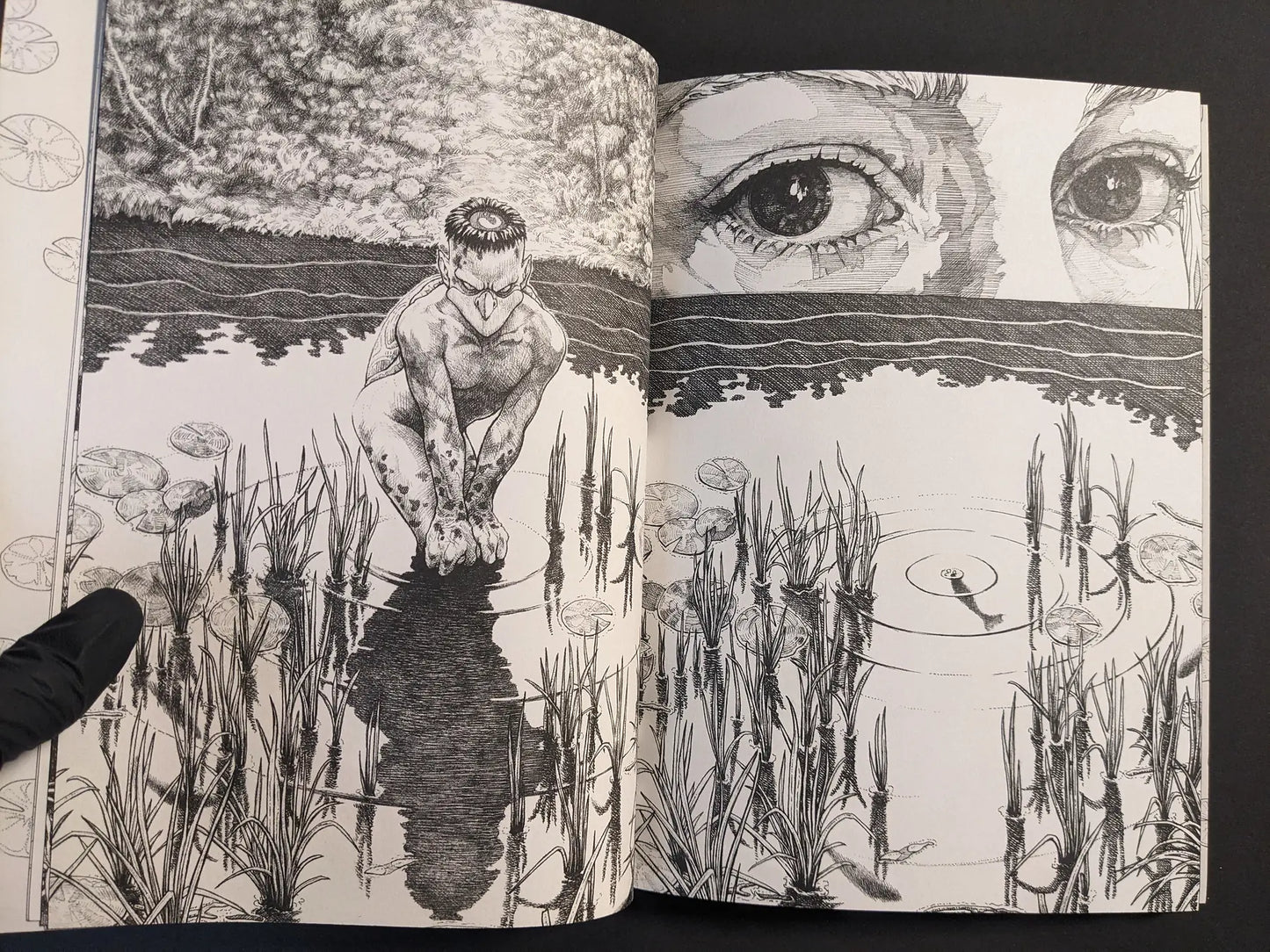 Interior spread with a kappa-like figure by water and large eyes above the horizon, black-and-white ink