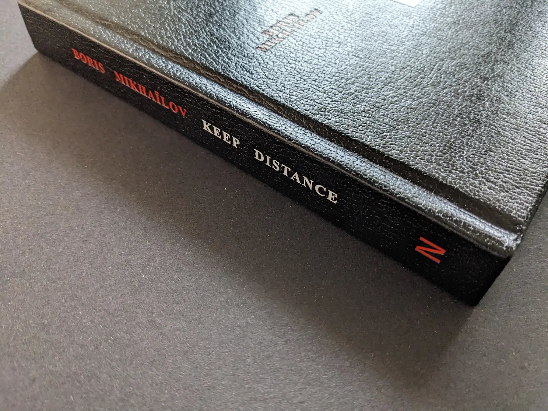 Spine of the black hardcover photobook Keep Distance by Boris Mikhailov.