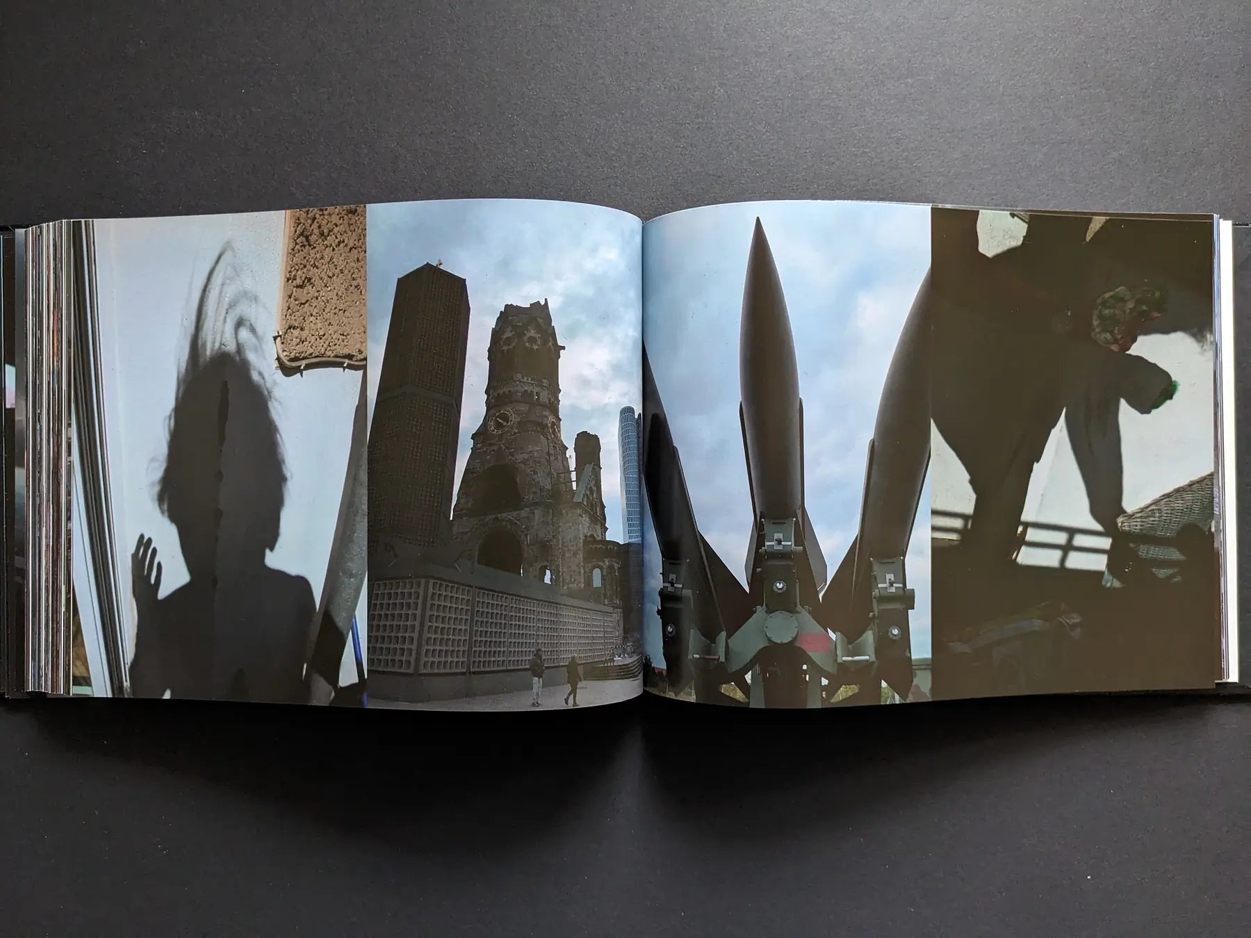 Shadow silhouette, a damaged church tower and upright missiles forming a tense urban landscape in Keep Distance by Boris Mikhailov.
