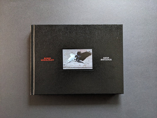 Front cover of Keep Distance by Boris Mikhailov with central photograph of a white bird and a black bird against a black leather-like background.