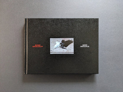 Front cover of Keep Distance by Boris Mikhailov, with a white bird and a black bird on a black textured cover.