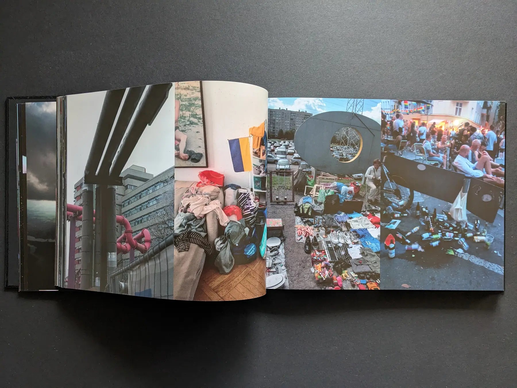 Interior spread with city pipework, a sofa piled with clothes, a flea-market stall, and a crowded street gathering.