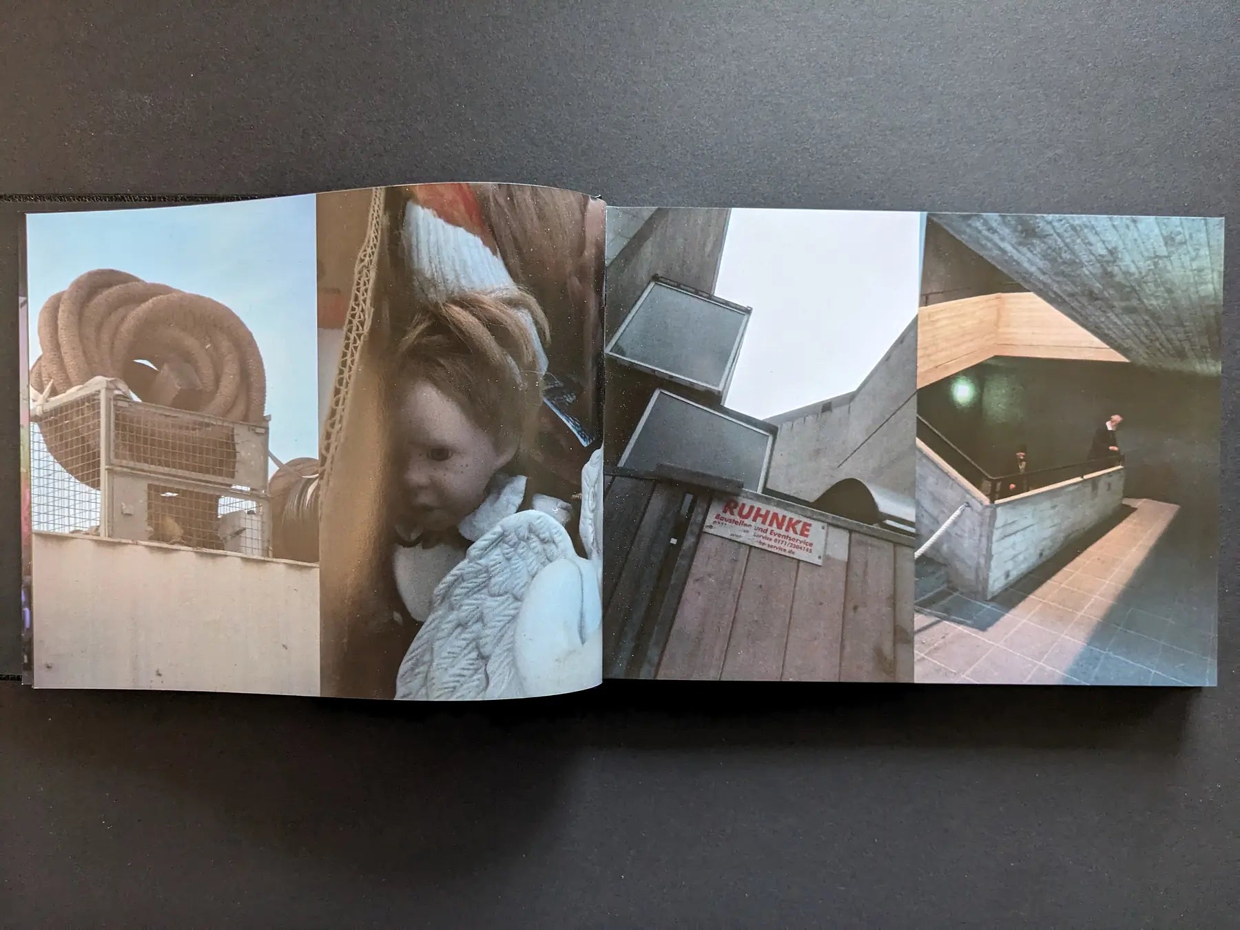 Interior spread with vertical colour photographs of a coiled hose, a doll, concrete architecture, and people on stairs.