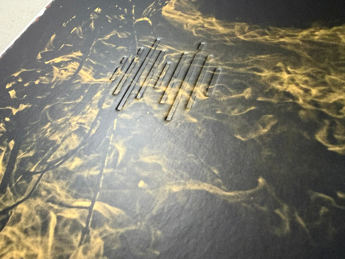 Close-up of the black cover with gold smoke-like pattern and embossed title detail on Kurayami.