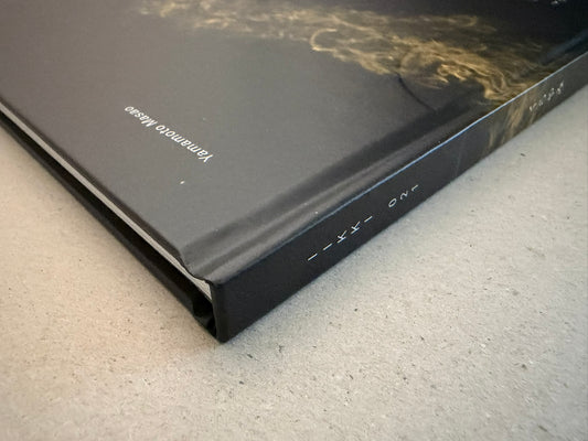 Kurayami hardcover shown at an angle, with the black spine and cover edge visible against a grey surface.