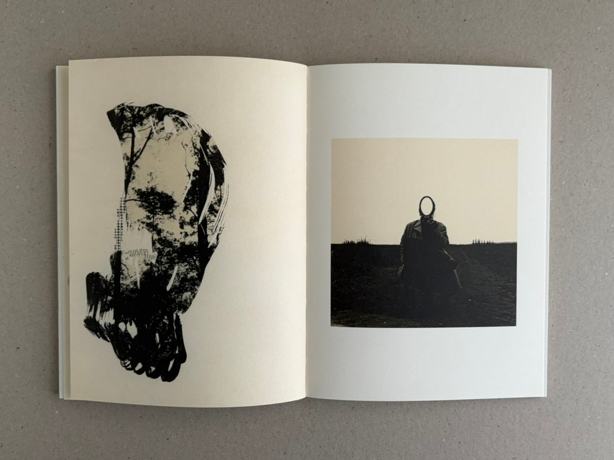 Open photobook spread from Lejos De La Tierra – Irene Zottola, showing a black abstract figure on the left page and a small dark landscape photograph on the right page.