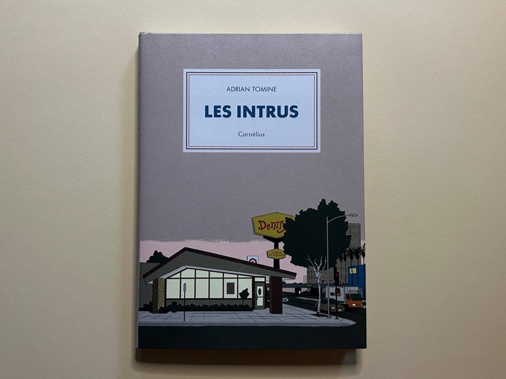 Les Intrus by Adrian Tomine, front cover with a grey jacket and a diner scene at the bottom