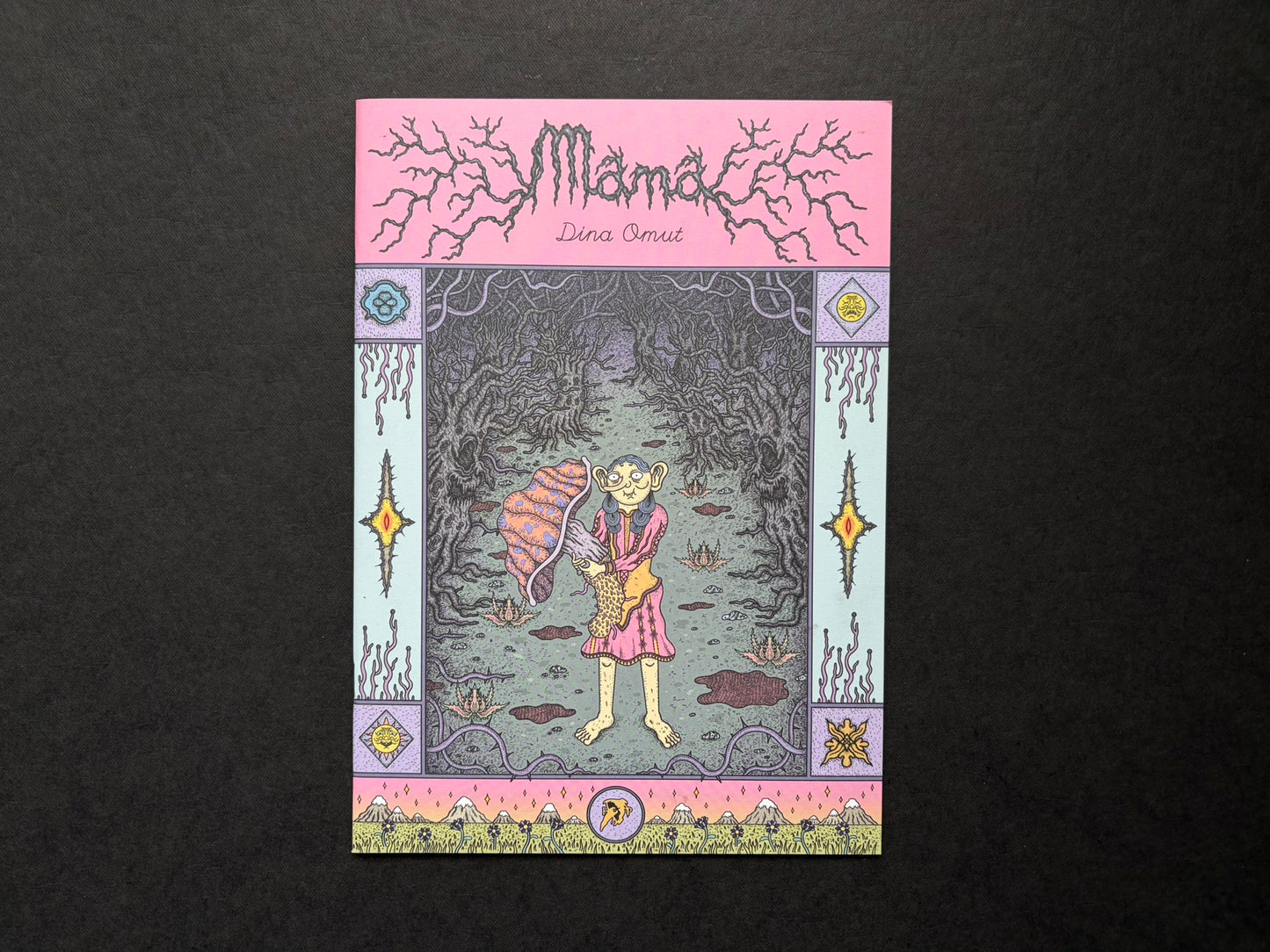 Mana by Dina Omut, front cover on a dark fabric background