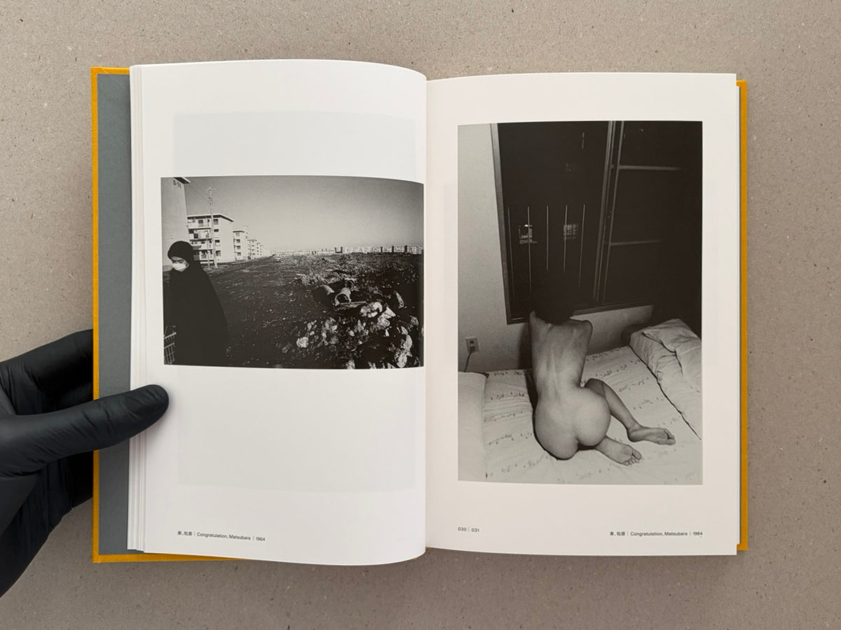Open spread of Masahisa Fukase 1961–1991 Retrospective showing two black-and-white photographs, with a page number at the bottom center and a gloved hand holding the book.