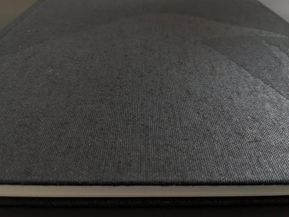 Close-up of the black linen hardcover of "Ravens" showing embossed raven silhouette.