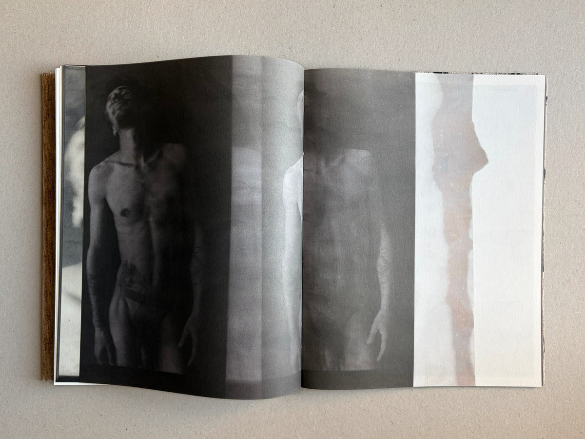 Materia by Vic Bakin, open photobook spread showing a faded male figure across dark and pale pages.