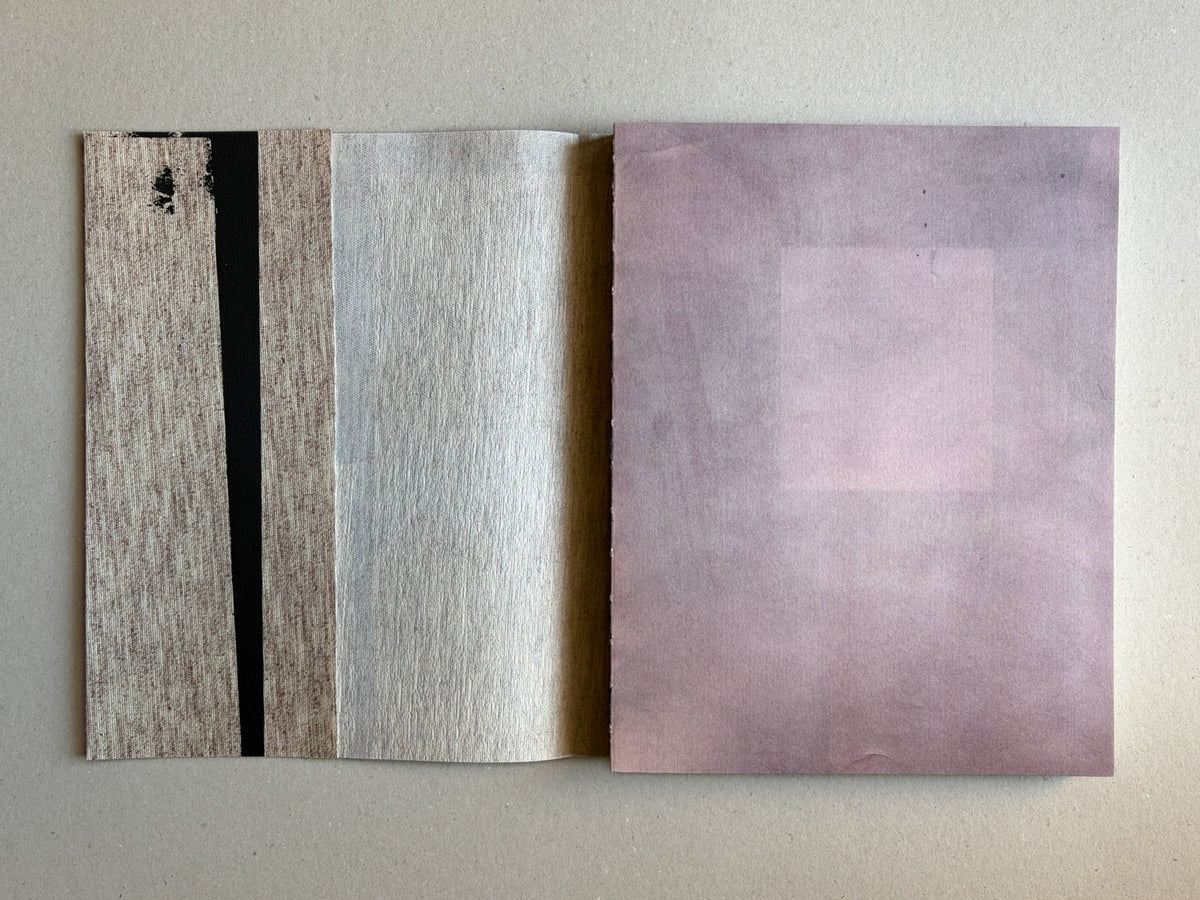 Materia by Vic Bakin, open book showing a textured spread with muted beige, grey, and pale pink pages