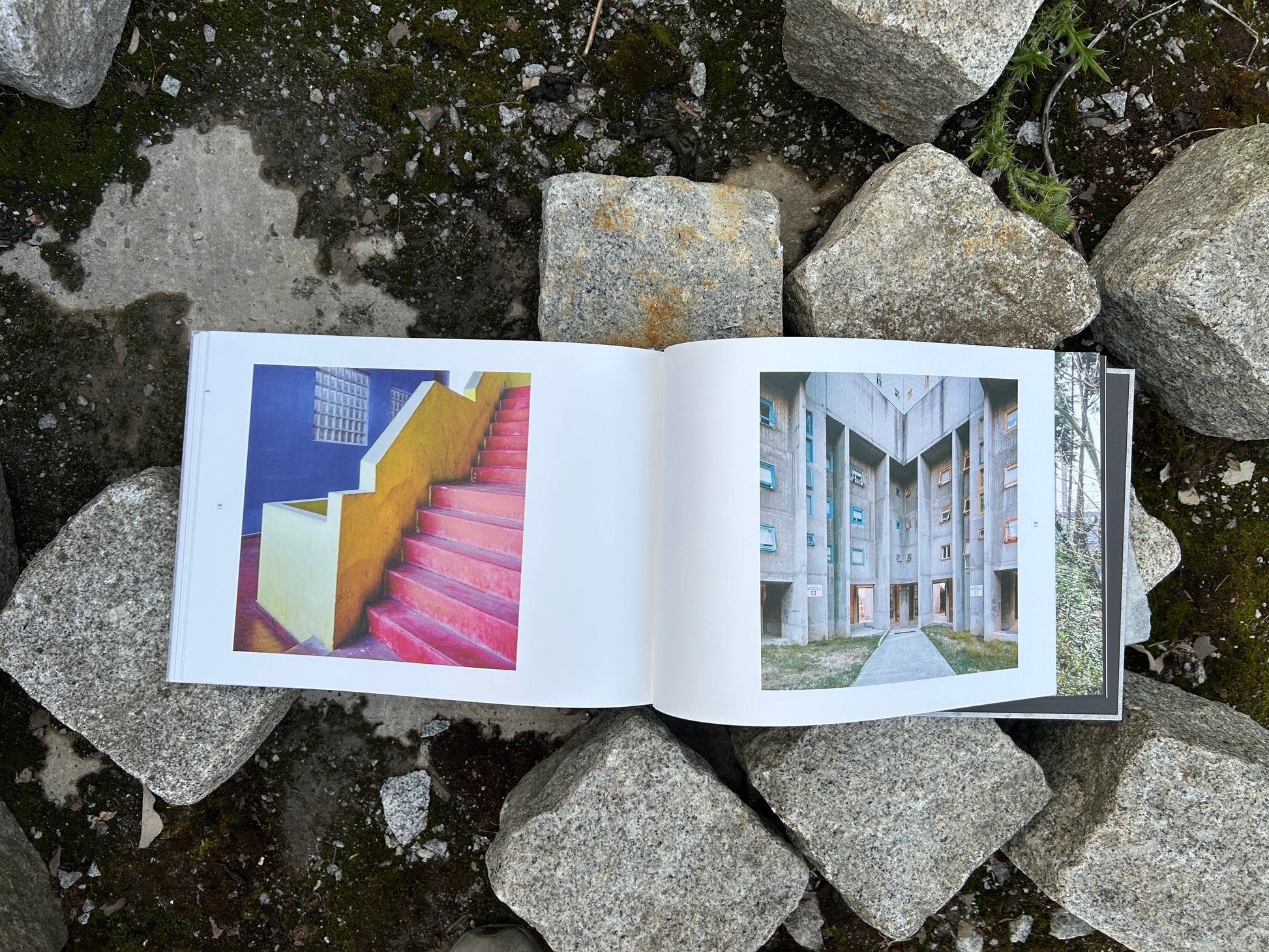Book 'Alveare' by Matthias Heiderich and Andrea Belfi open to pages with vibrant red stairs and a brutalist residential complex - IIKKI - Lokator100