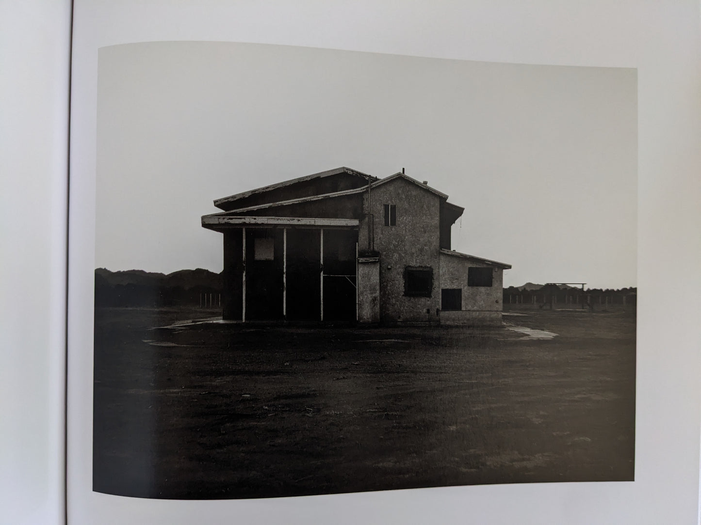 Large derelict desert building at dusk with boarded windows