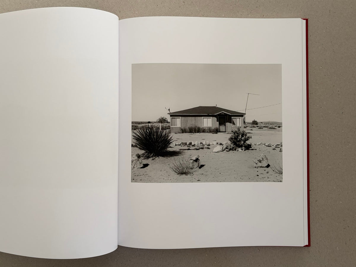 Open spread of Message from the Exterior by Mark Ruwedel, showing a black-and-white photograph of a small desert house on the right-hand page.
