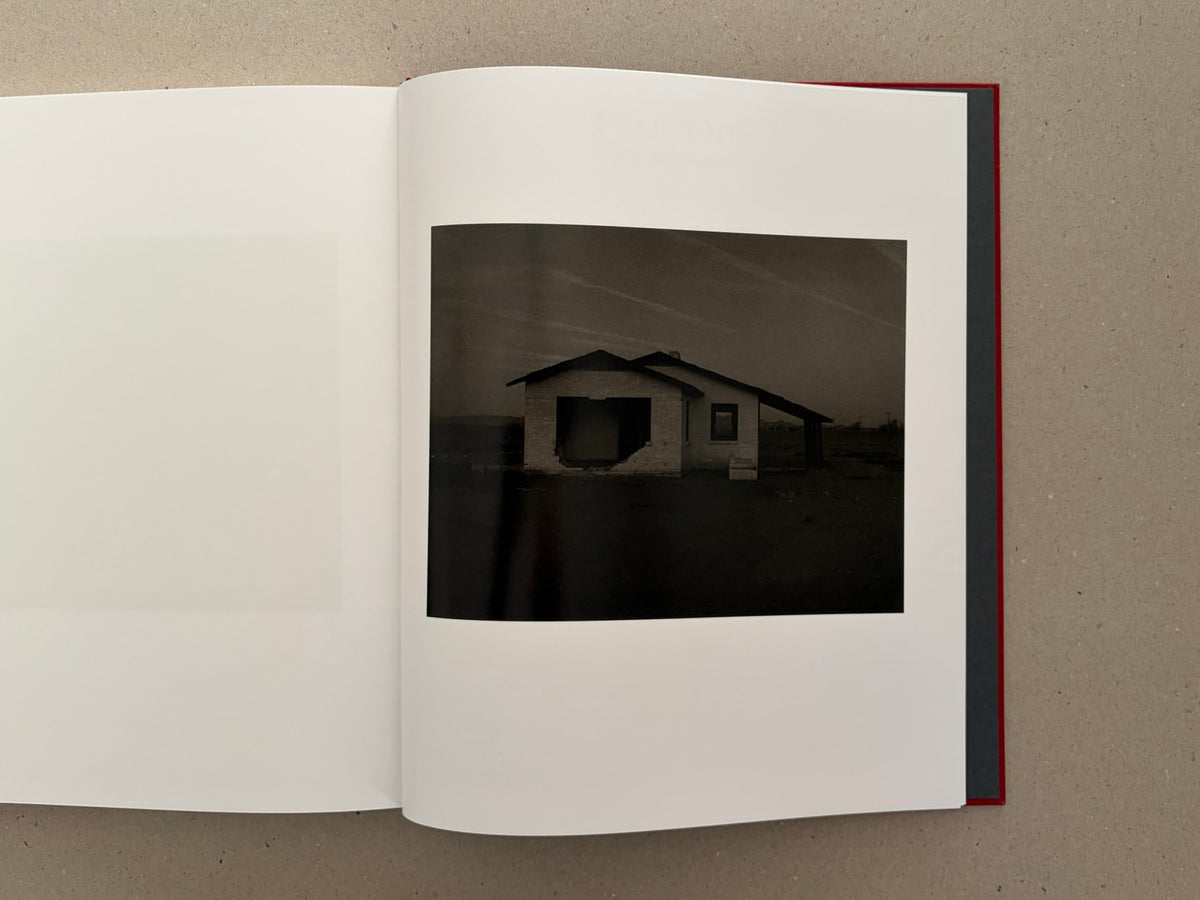 Open book spread showing a dark photograph of an abandoned house in Message from the Exterior by Mark Ruwedel.