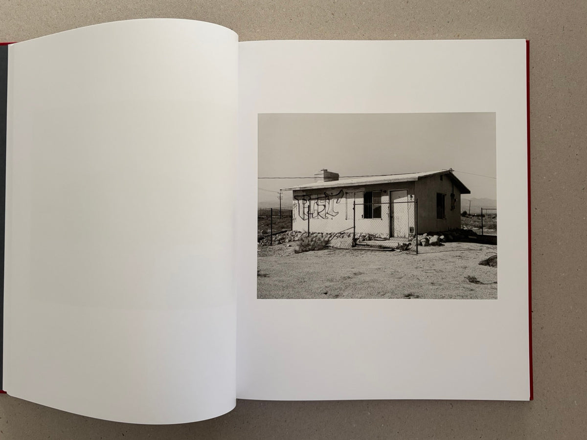 Open spread of Message from the Exterior by Mark Ruwedel, showing a black-and-white photograph of a small desert house on the right-hand page.