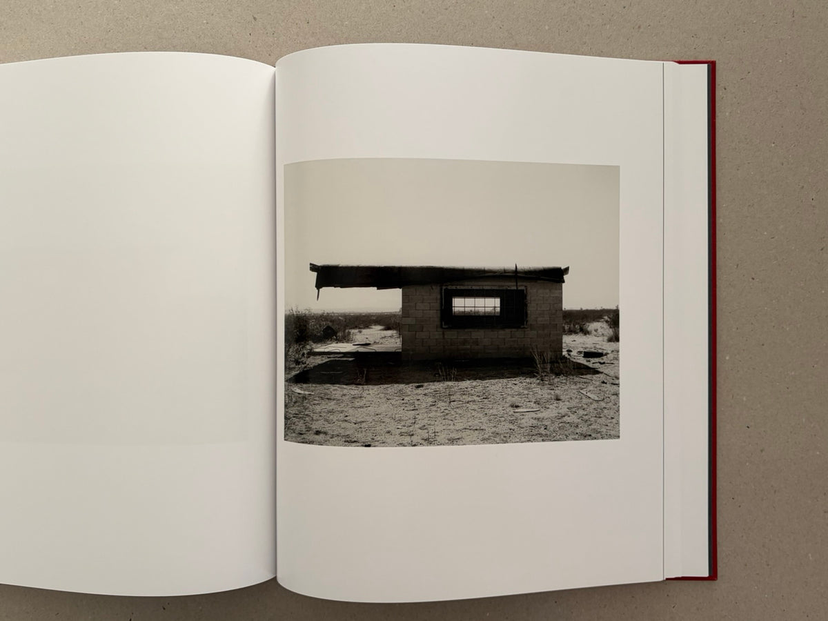 Open book spread from Message from the Exterior by Mark Ruwedel, showing a photograph of a small abandoned desert structure on the right-hand page.