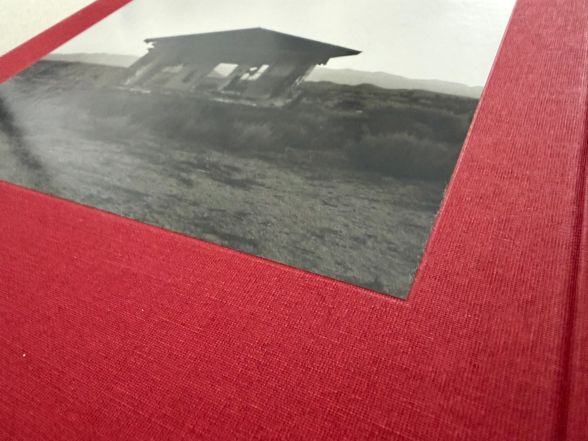 Close-up of the red cloth cover of Message from the Exterior by Mark Ruwedel, with a tipped-in black-and-white desert house photograph.