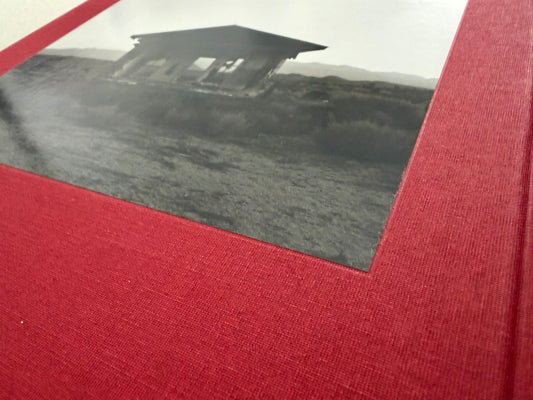 Close-up of the red cloth cover of Message from the Exterior by Mark Ruwedel, with a tipped-in black-and-white desert house photograph.