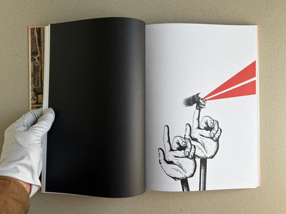 Open spread of METAFABLES: The Art of Andrew Blucha, showing a black left page and a right page with a black line drawing of hands holding a skull emitting two red beams.
