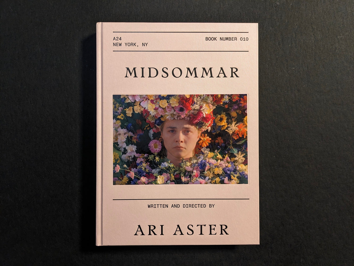 Front cover of the Midsommar screenplay book by Ari Aster, showing Dani surrounded by flowers.