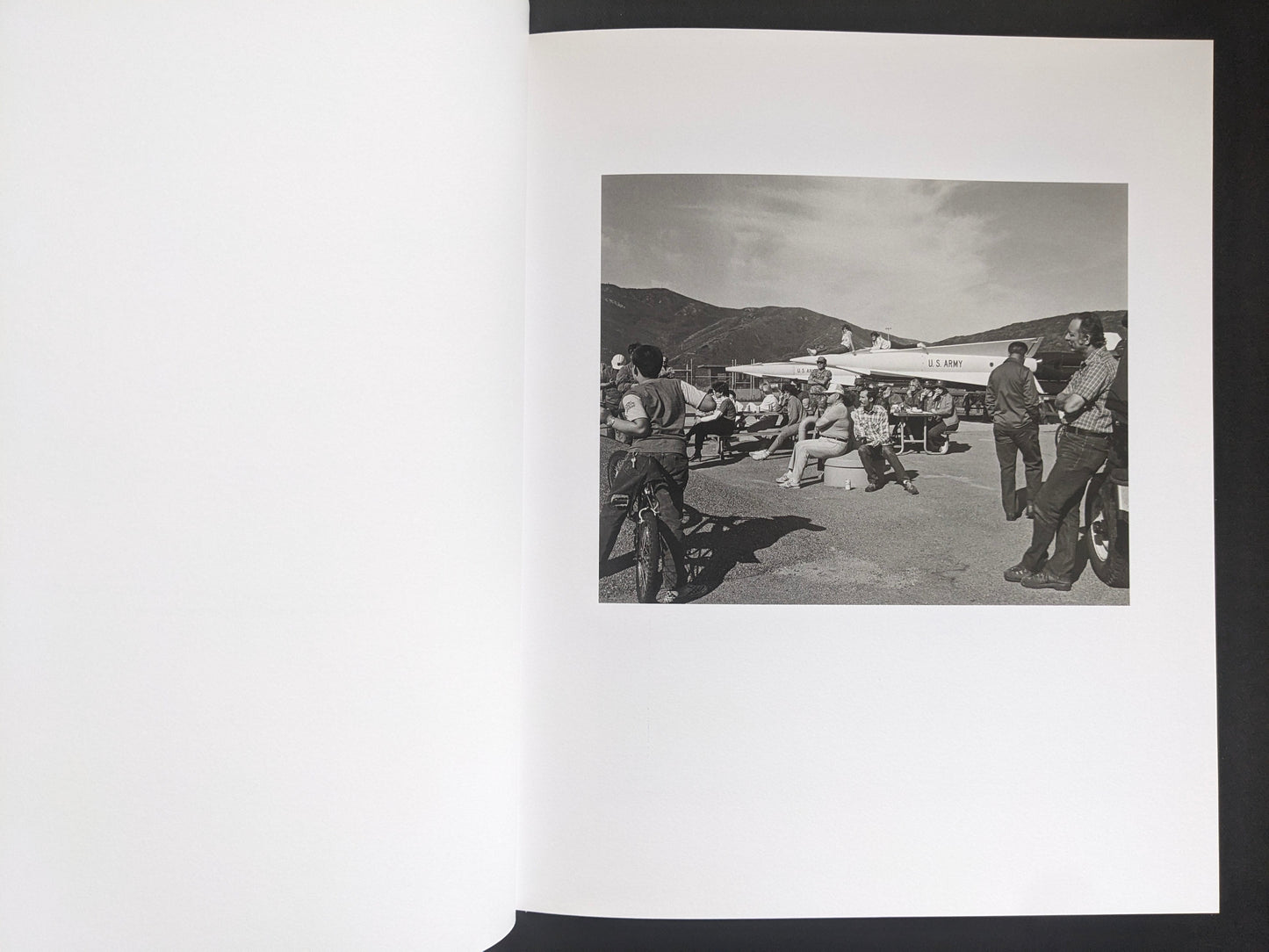 Interior spread from Mimi Plumb’s Landfall showing people gathered near an aircraft on an airfield.