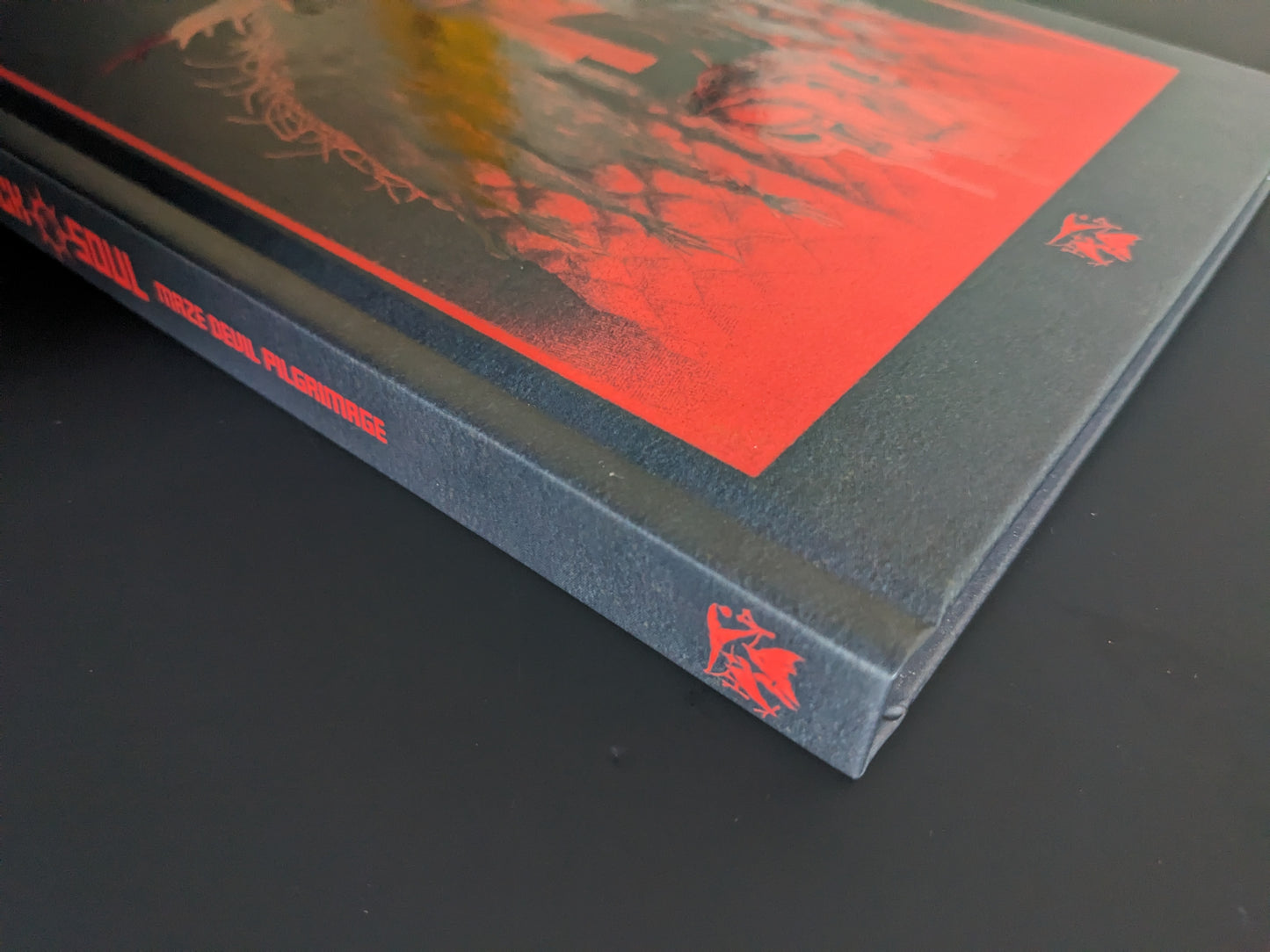 Book spine of Mock Soul – Maze Devil Pilgrimage with title in red on black hardcover and Hollow Press logo.