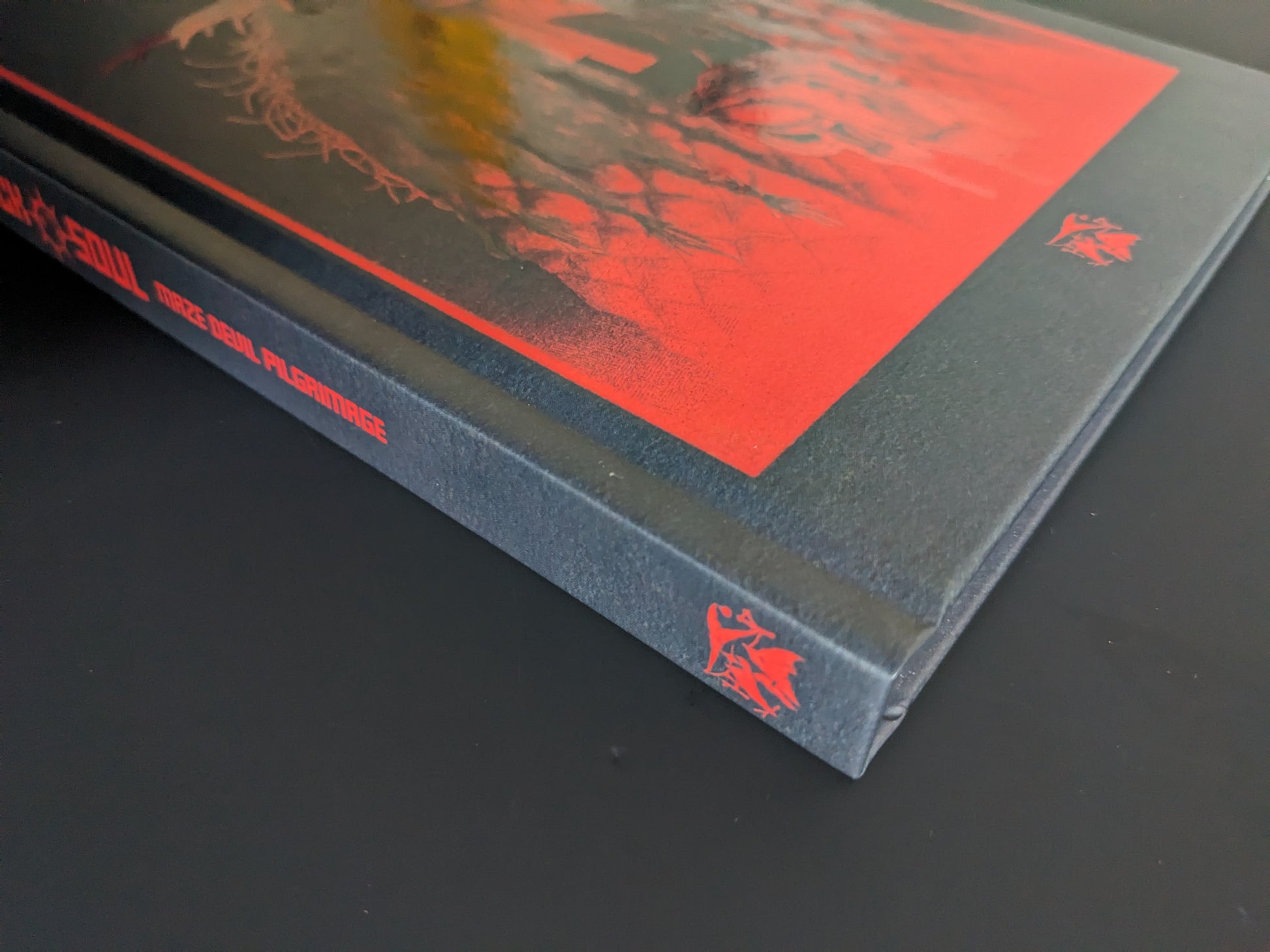 Book spine of Mock Soul – Maze Devil Pilgrimage with title in red on black hardcover and Hollow Press logo.