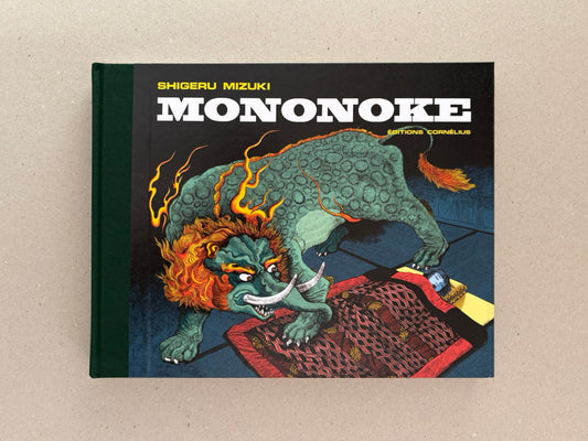 Front cover of Mononoke by Shigeru Mizuki, showing a green yokai crouched over a patterned textile.