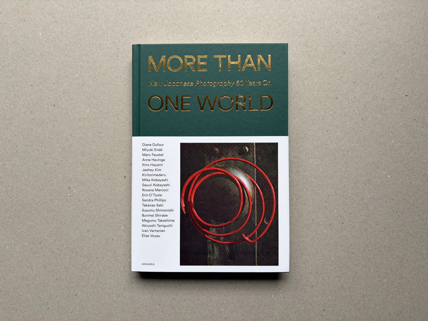 Front cover of More Than One World – New Japanese Photography 50 Years On, showing the title in gold on a green and white cover with a photograph inset below.