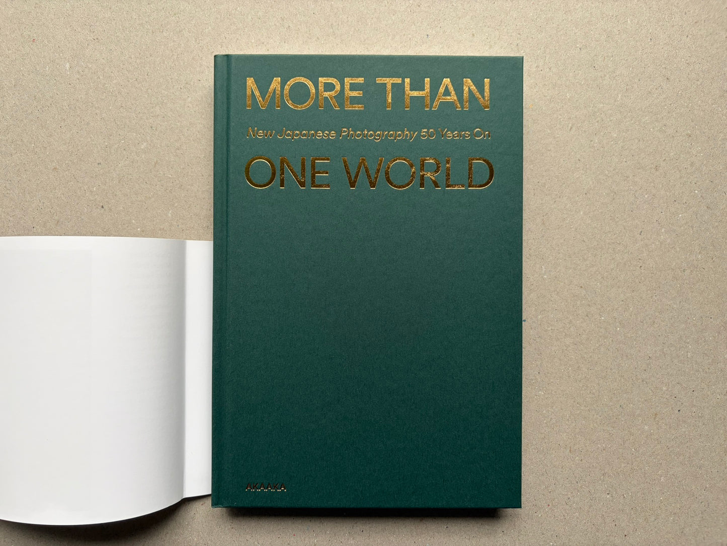 Back cover of More Than One World – New Japanese Photography 50 Years On, with the title in gold on a plain green field and a white band at the bottom.