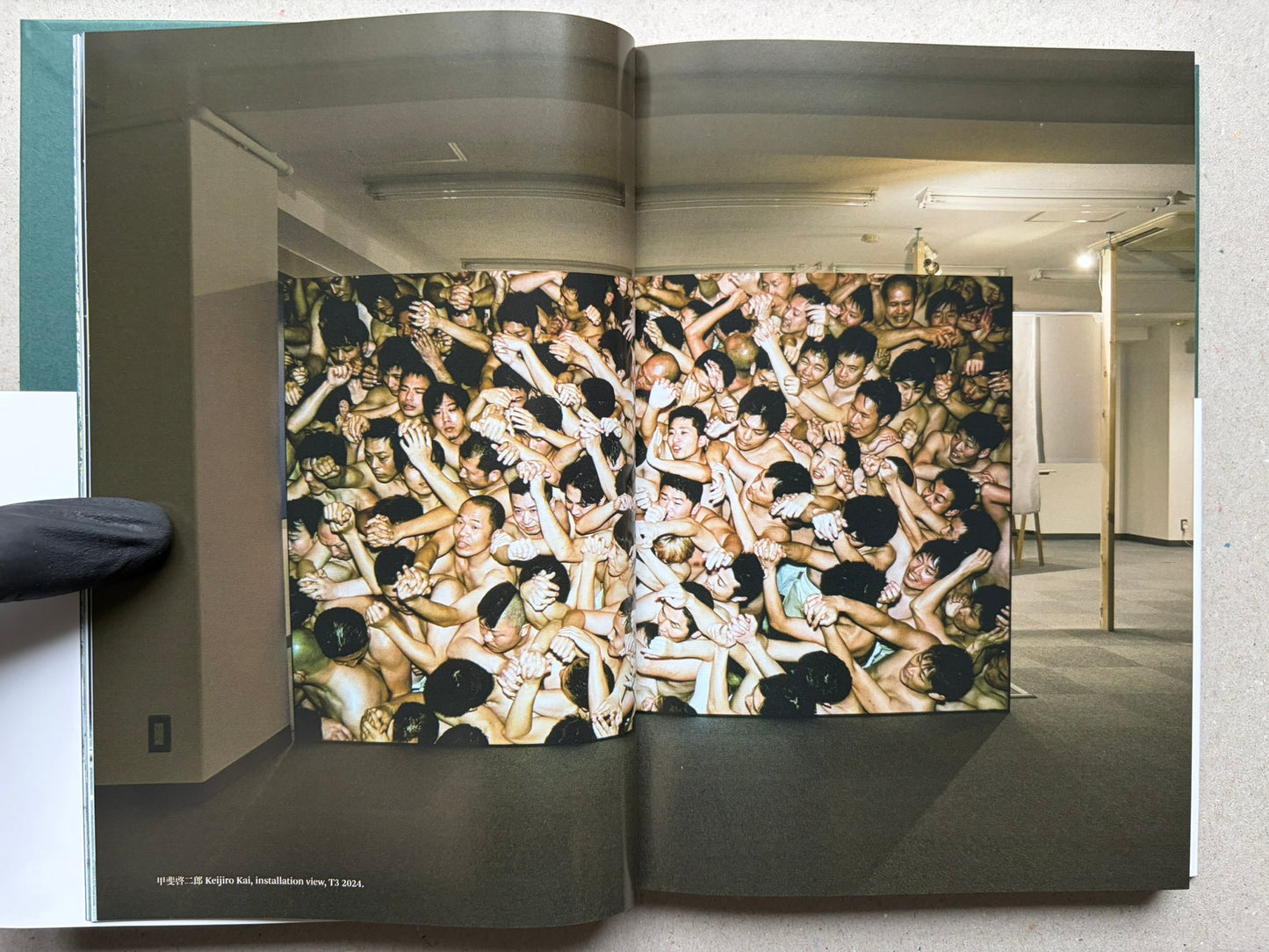 Open book spread from More Than One World – New Japanese Photography 50 Years On, showing a full-bleed crowd photograph across the left page.