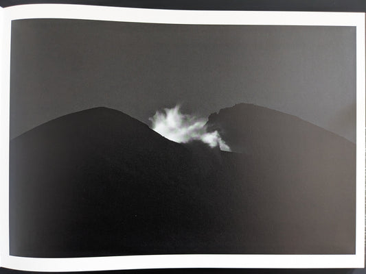 Black and white photo of rock silhouette with rising smoke, from New Land