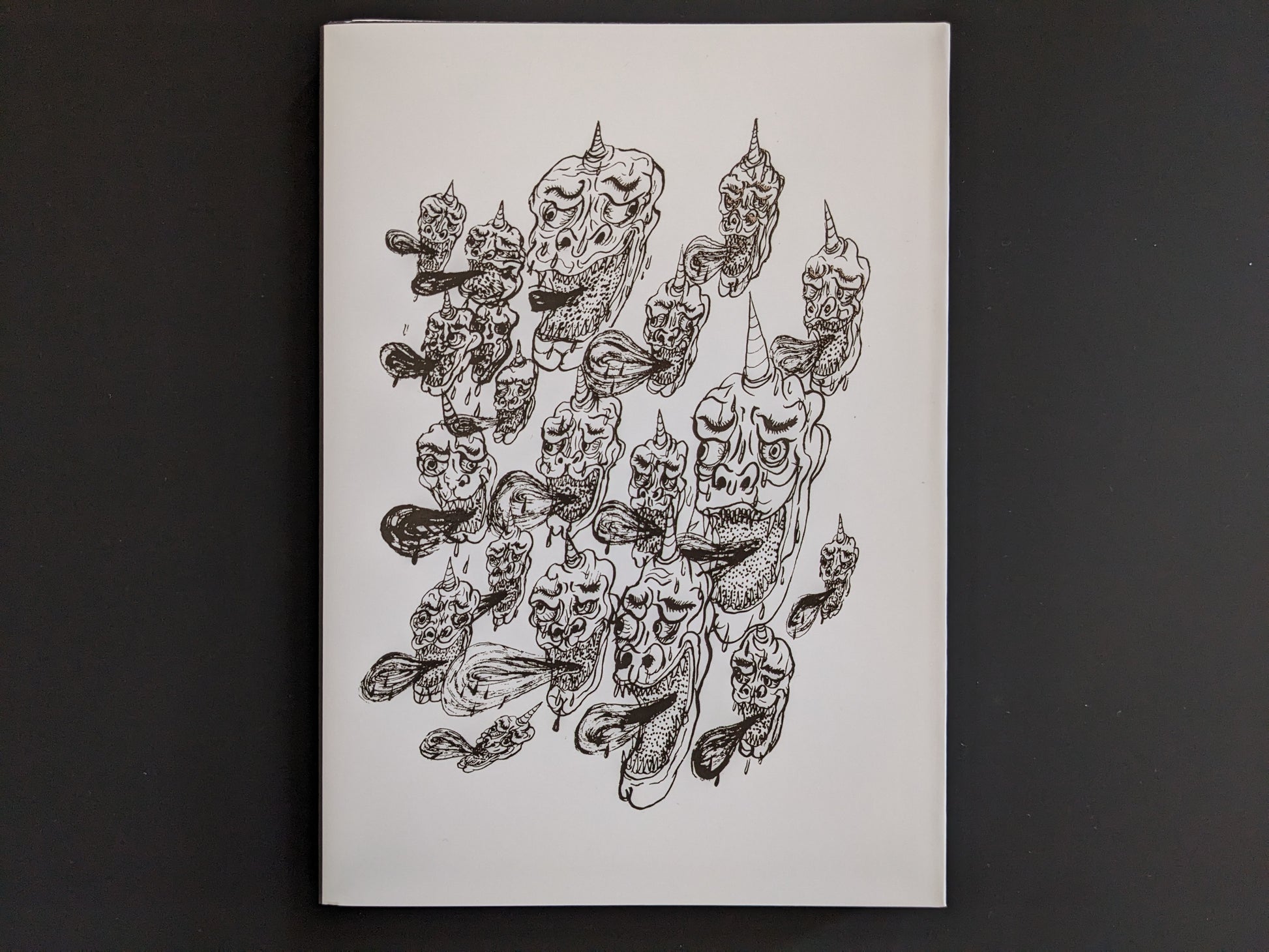 Back cover of The Life of Namazuko featuring a pattern of grotesque demon heads with horns and flowing tongues.