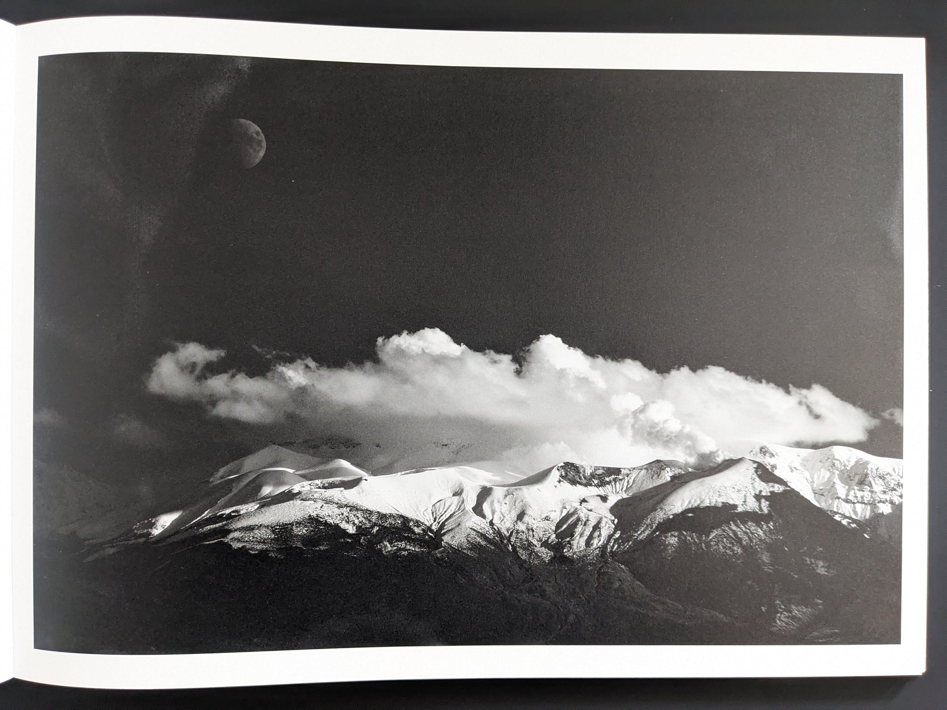 Clouds, a mountain ridge, and the moon in monochrome