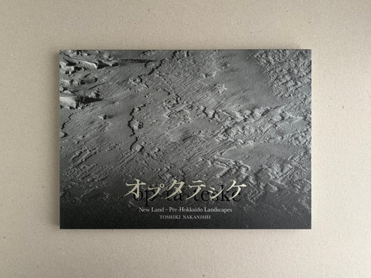 Front cover of New Land: Pre-Hokkaido Landscapes by Toshiki Nakanishi, showing a textured black-and-grey landscape image with the title printed near the bottom.