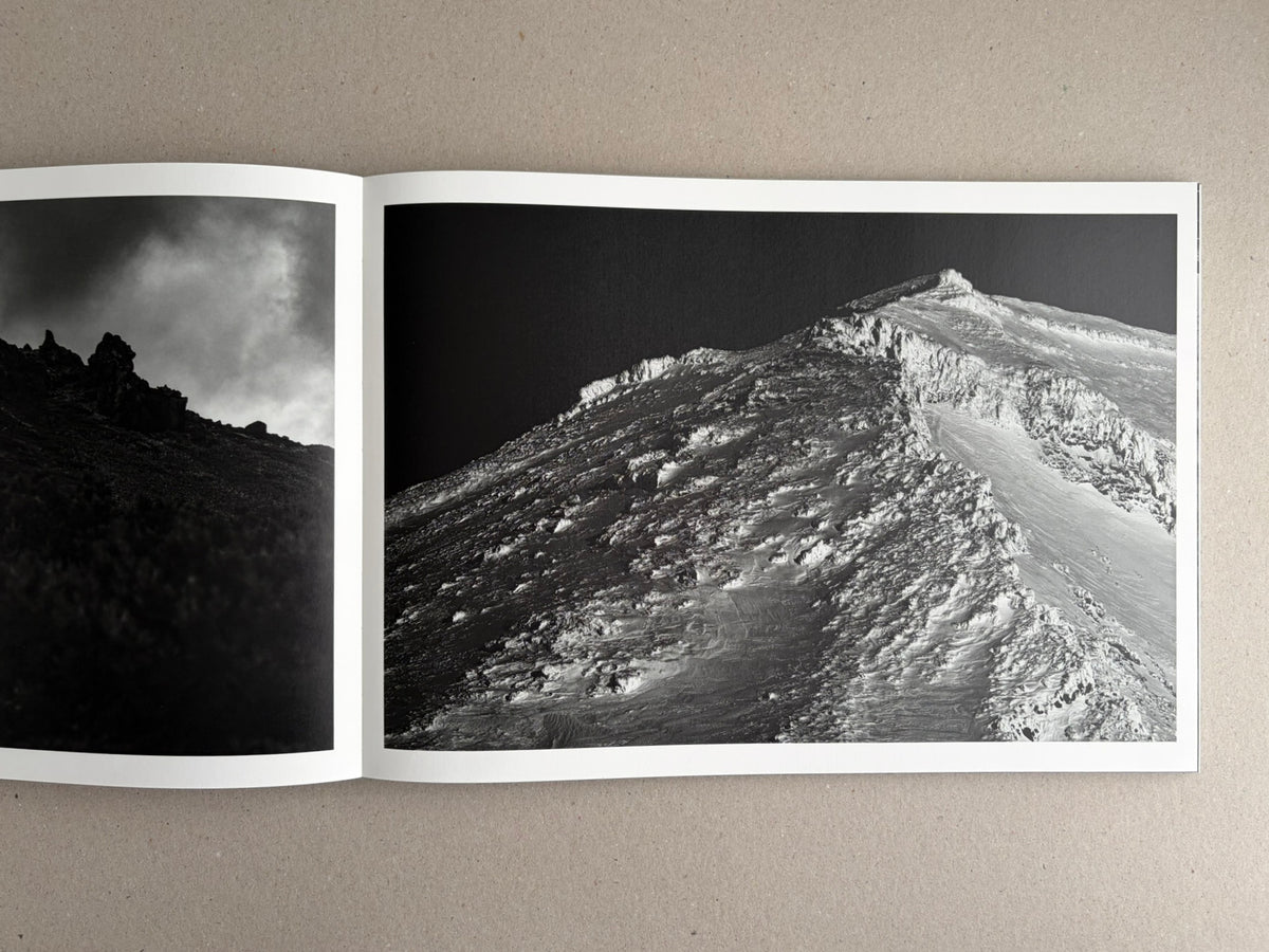 Open photobook spread from New Land: Pre-Hokkaido Landscapes by Toshiki Nakanishi, showing two black-and-white landscape photographs.